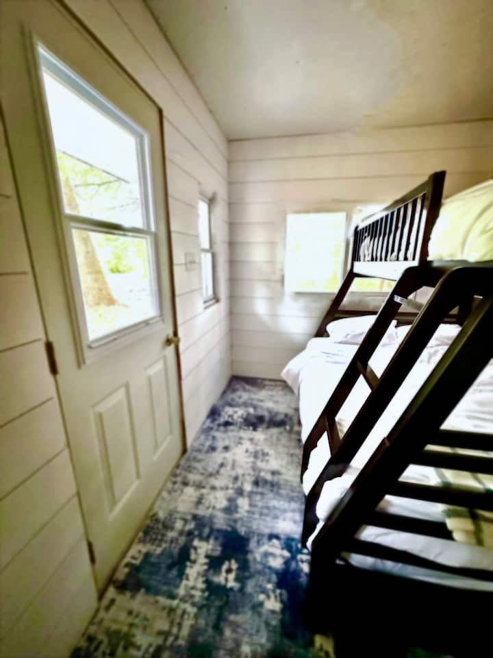 Оваа новореновирана удобна дрвена колиба има прекрасен поглед кон езерото.  Се наоѓа на само неколку чекори од терасата на викендичката и нуди бонус простор за спиење со единечен кревет на спрат.  Има централно светло, приклучок за вентилатор и приклучоци за полнење на телефонот.  