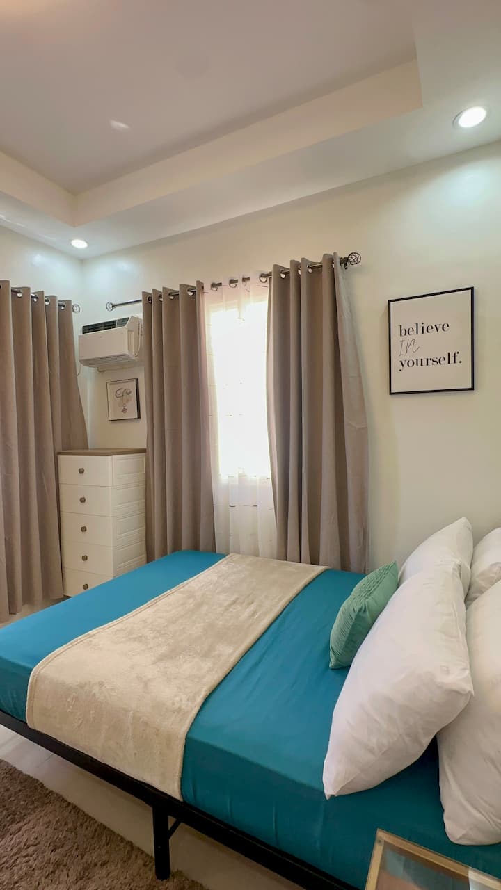 Full-size bed with fresh linens and soft pillows
	•	Blackout curtains and sheer drapes for light control
	•	Wall-mounted air conditioning unit
	•	Positive wall art for a uplifting vibe
	•	Cozy blanket and textured area rug for added comfort
