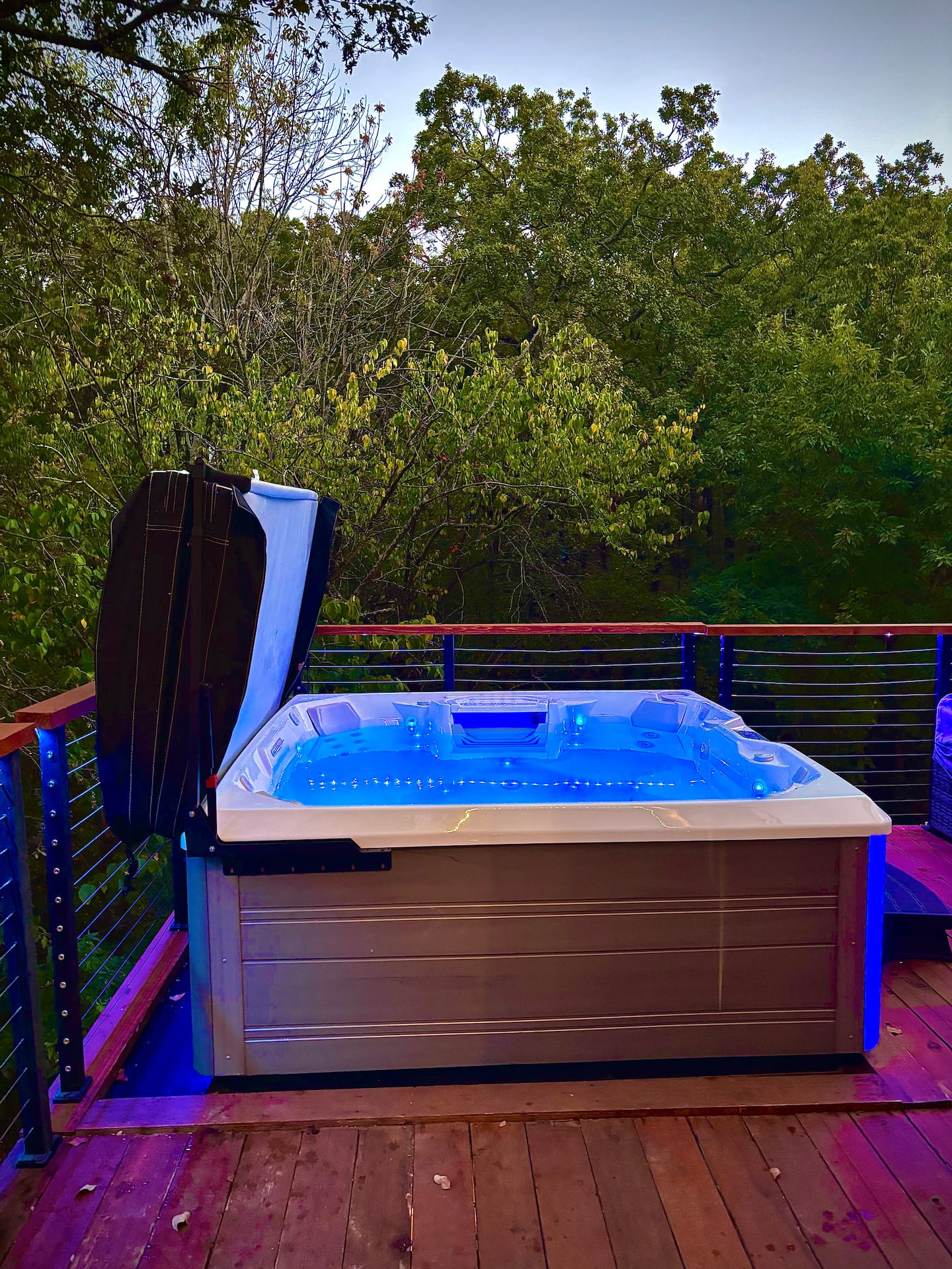 Saltwater hot tub with blue LED lighting on private deck with treetop views
