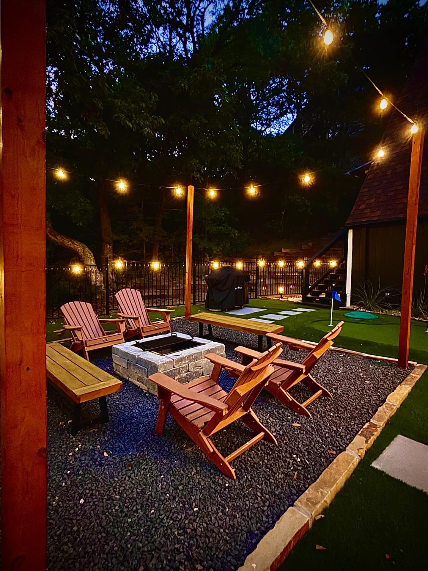 Fire pit with Adirondack chairs and string lights at dusk