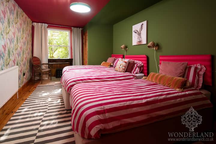 Esta habitación vibrante y excéntrica combina múltiples historias y temas del País de las Maravillas, utilizando colores atrevidos. Cuenta con tres camas individuales, un vestidor y un cuadro de la liebre, que invita a la valentía, la alegría y la risa para explorar este espacio tan caprichoso.