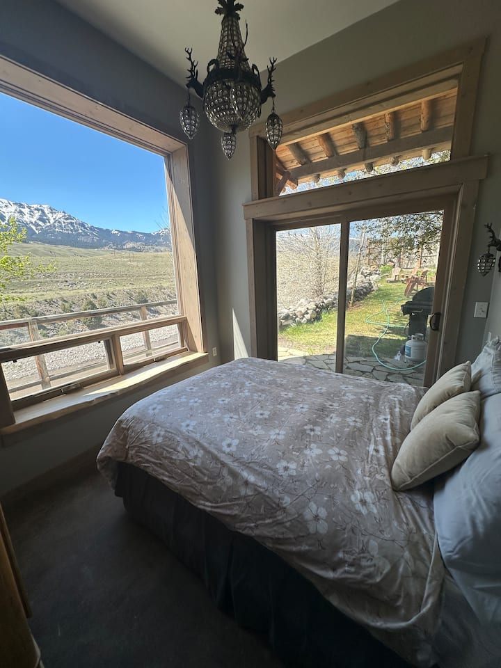Bedroom with its own bathroom, a queen bed and doors that open onto the side lawn and the deck.