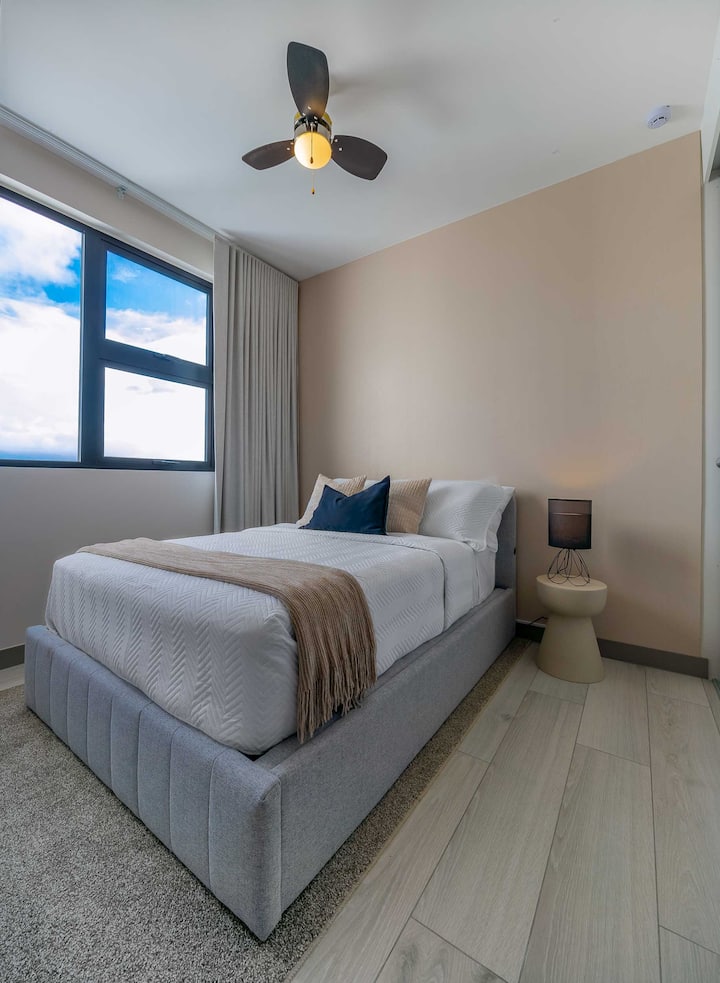 Მყუდრო მეორე საძინებელი სრული ზომის საწოლით, რბილი ბუნებრივი განათებით და ტელევიზორით დასასვენებლად.