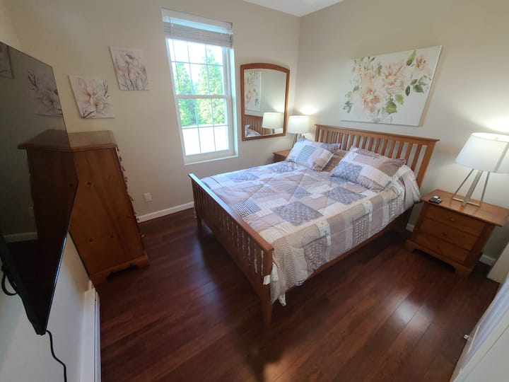 Примамлива спална соба со брачен кревет, пријатно осветлување, дрвен мебел и мека постелнина за мирен сон.