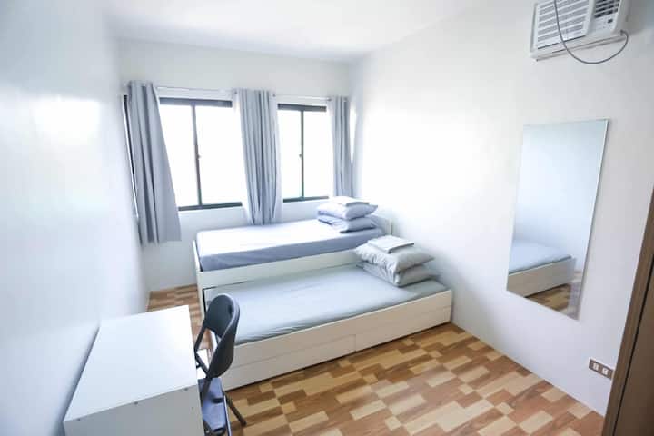 ห้องนอนที่ 2 มีเตียงเดี่ยว 2 เตียง โต๊ะข้างเตียง โต๊ะทำงานพร้อมเก้าอี้ กระจกขนาดใหญ่ ตู้เสื้อผ้าพร้อมไม้แขวนเสื้อผ้า และผ้าม่านสีดำ