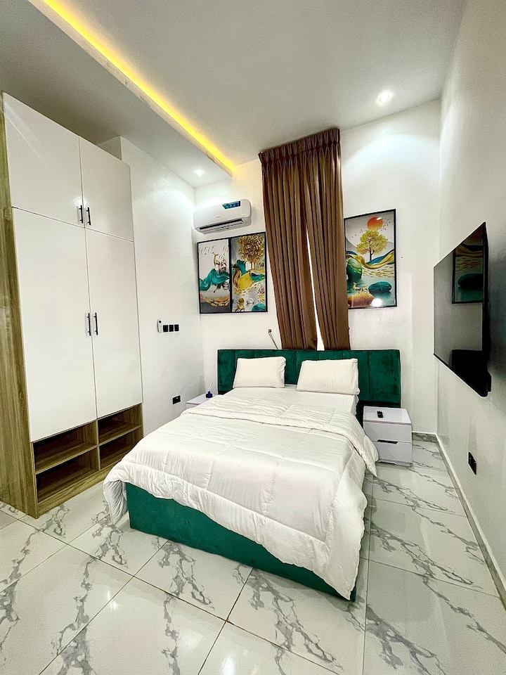 Dormitorio queen cómodo y elegante con una suave cama tamaño queen, sábanas acogedoras, armario, aire acondicionado e iluminación cálida, ideal para noches tranquilas y una estancia relajante.