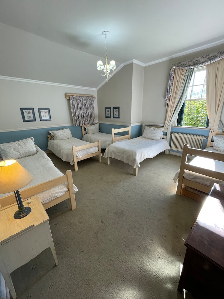 Habitación grande con 5 cómodas camas y baño adjunto.