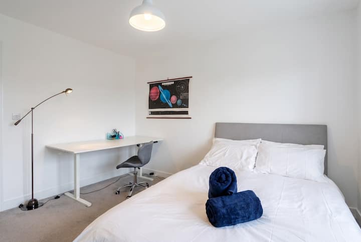 Cama matrimonial con un escritorio y un espacio de trabajo al lado de la cama.