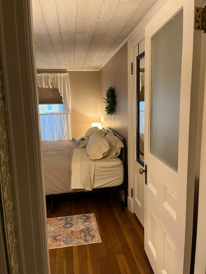 Душек од пена со големина на брачен кревет (широк 14 инчи) Достапни се сите постелнини. Затемнети нијанси. 32 инчен Roku телевизор. Клима уред. Маса за полнење на уредите. 