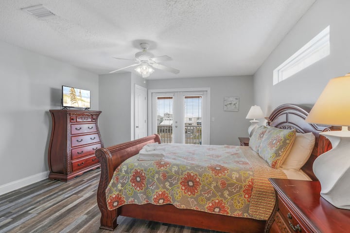 Despiértate con una suave luz natural y vistas a la costa desde este acogedor dormitorio con acceso privado al balcón.