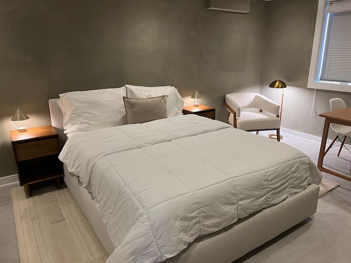 ห้องนอนที่อบอุ่นพร้อมเตียงควีนไซส์ พื้นที่อ่านหนังสือ และโต๊ะทำงาน 