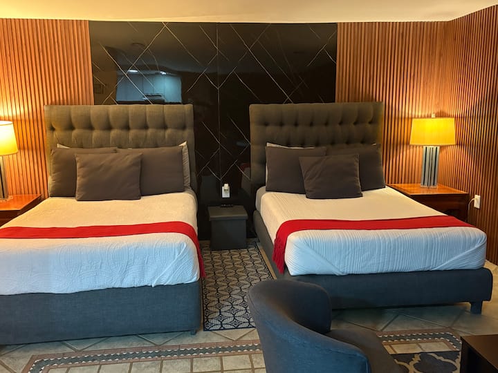 غرفة نوم بها سريران بحجم كوين وسرير أريكة بحجم كوين أيضًا.