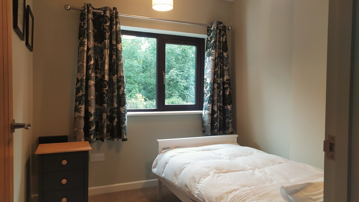 Un elegante dormitorio individual en la planta baja. Incluye espacio para colgar y armario de noche. Cómodo acceso al baño de la planta baja.