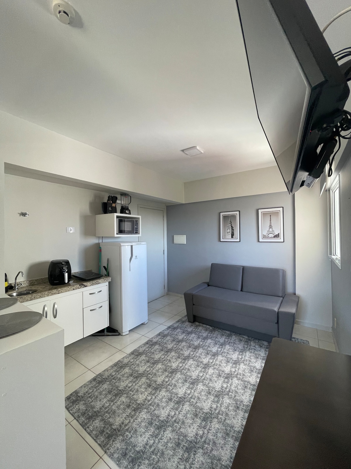 Dhomë e integruar me kuzhinë, e pajisur me divan dopio, hapësirë ngrënieje me jashtëqitje, frigorifer, sobë me induksion elektrik dhe ventilator ajri 