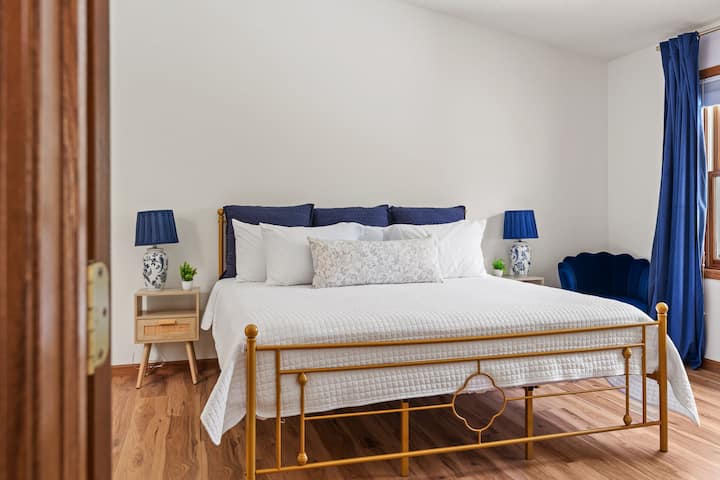Chambre lumineuse avec lit king size doré élégant, touches bleues et parquet chaleureux