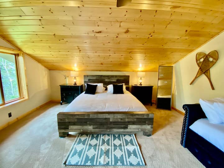 سرير كينج في غرفة النوم الرئيسية مع نافذة ذات صورة للاستمتاع بإطلالات على بحيرة سوبيريور والطبيعة.