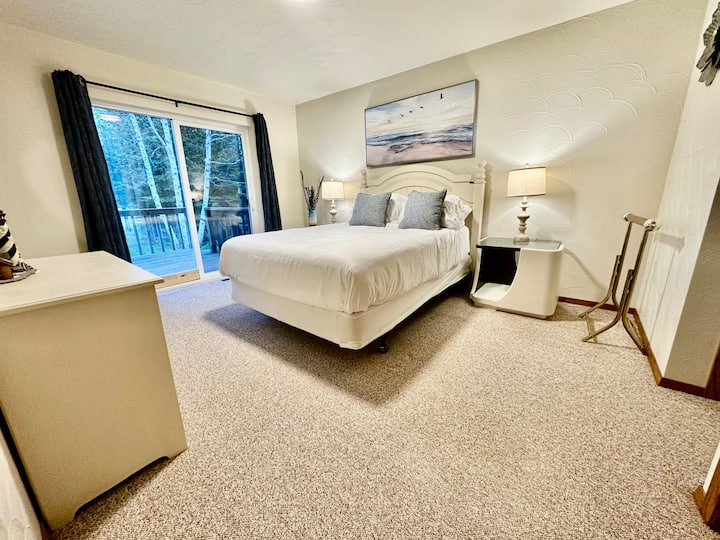 غرفة نوم واسعة بسرير كوين مع شرفة للمشي وإطلالة على بحيرة سوبيريور من السرير