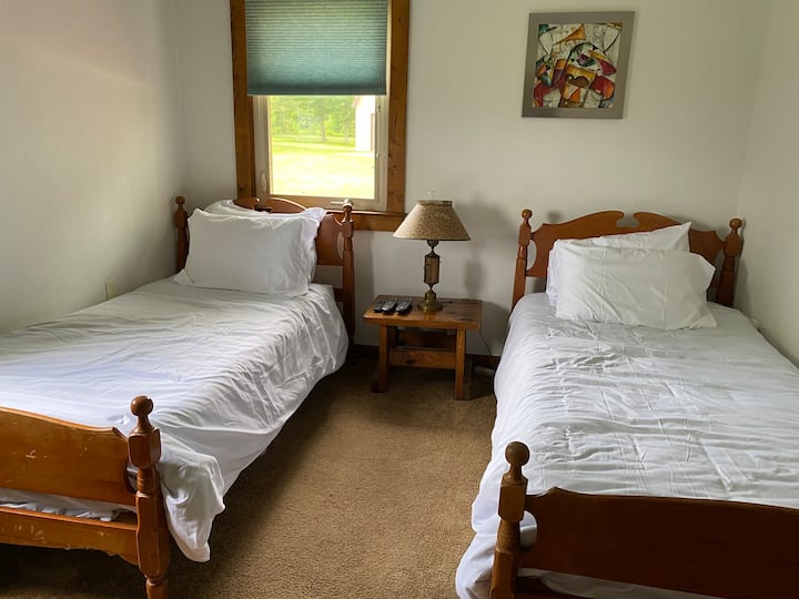 Спалня за гости с две единични легла. Луксозно памучно спално бельо на леглата с резервни одеяла в шкафа и преносим вентилатор на разположение на гостите. 