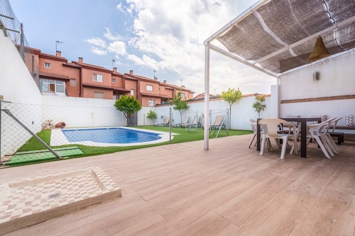 Terraza de madera con pérgola y comedor exterior.