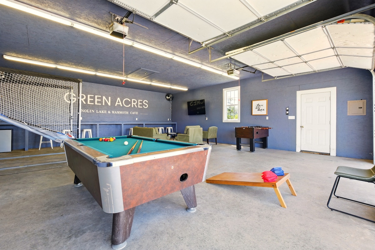 The game room features a vibrant blue wall and a well-lit atmosphere. A pool table is positioned centrally, with a foosball table nearby. Additional seating and game equipment, including a basketball game, are visible, inviting a fun and active space for guests.