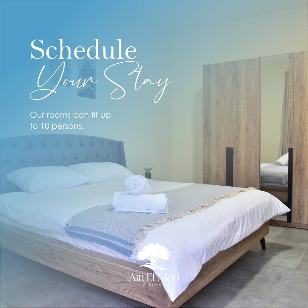 A spacious bedroom features a comfortable bed with crisp white bedding. Fresh towels are neatly arranged on the bed. A large wardrobe in a natural wood finish sits nearby, providing ample storage. Soft lighting contributes to the inviting environment.