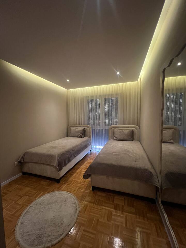 ห้องนอนที่สว่างและทันสมัยพร้อมเตียงเดี่ยวที่สะดวกสบาย 2 เตียง แสงไฟโดยรอบ และตู้เสื้อผ้าที่กว้างขวางมากพร้อมพื้นที่เก็บของมากมาย