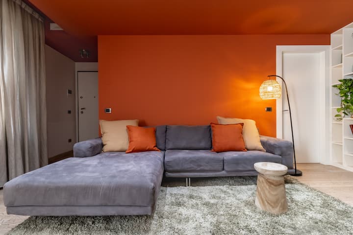 มุมมองของโซฟาเบดด้านหน้าที่มีพื้นหลังติดผนังดินเผาพรมแสงตัดกันด้านล่างและโคมไฟดีไซเนอร์ด้านข้างที่เพิ่มความทันสมัยให้กับสภาพแวดล้อมที่อบอุ่นและประณีต