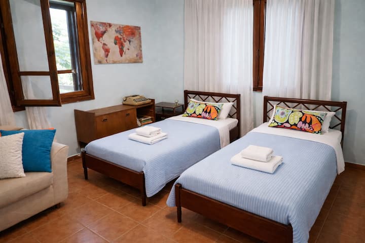 Notre chambre au rez-de-chaussée avec deux lits simples, de grands placards et un miroir avec les fenêtres donnant sur la mer et le jardin d'un côté et le jardin arrière de l'autre, juste à côté de la salle de bain principale et avec un ventilateur pour plus de confort.