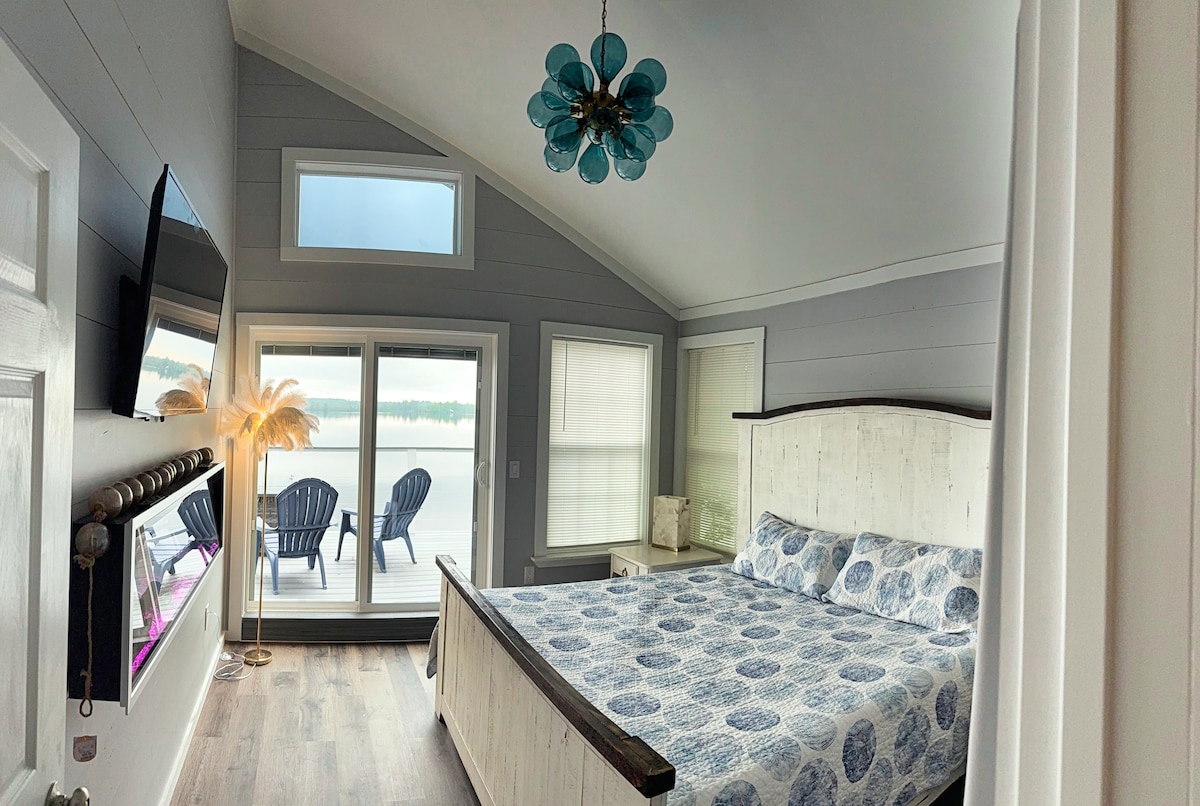 Slaapkamer 1: kingsize bed met een smart-tv, elektrische open haard en glazen schuifdeuren die uitkomen op het enorme terras met uitzicht op het meer.