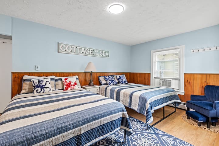 Habitación estilo motel con dos camas tamaño queen y TV.