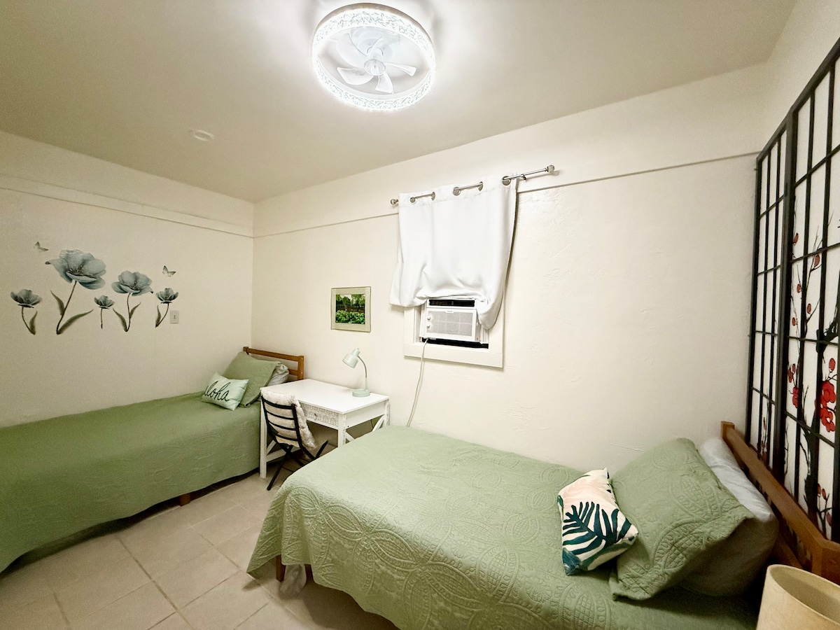 Spavaća soba s 2 odvojena kreveta, prozorskim klima-uređajem, stropnim ventilatorom i malim radnim stolom 
Napomena: stropni ventilator ima 2 smjera strujanja zraka: hladno ili toplo (odvlaživanje). Molimo vas da koristite stropni ventilator (ili čepić za uši) tijekom spavanja ako je klima-uređaj na prozoru bučan.