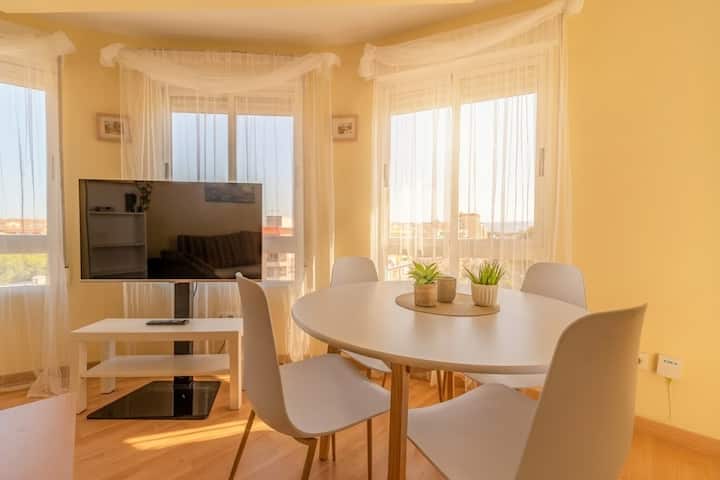 Salón con mirador acristalado, TV y mesa de comedor.