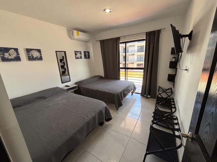Quarto com cama de casal, com baús, espelho, ar condicionado, TV e cortinas blackout a 80%