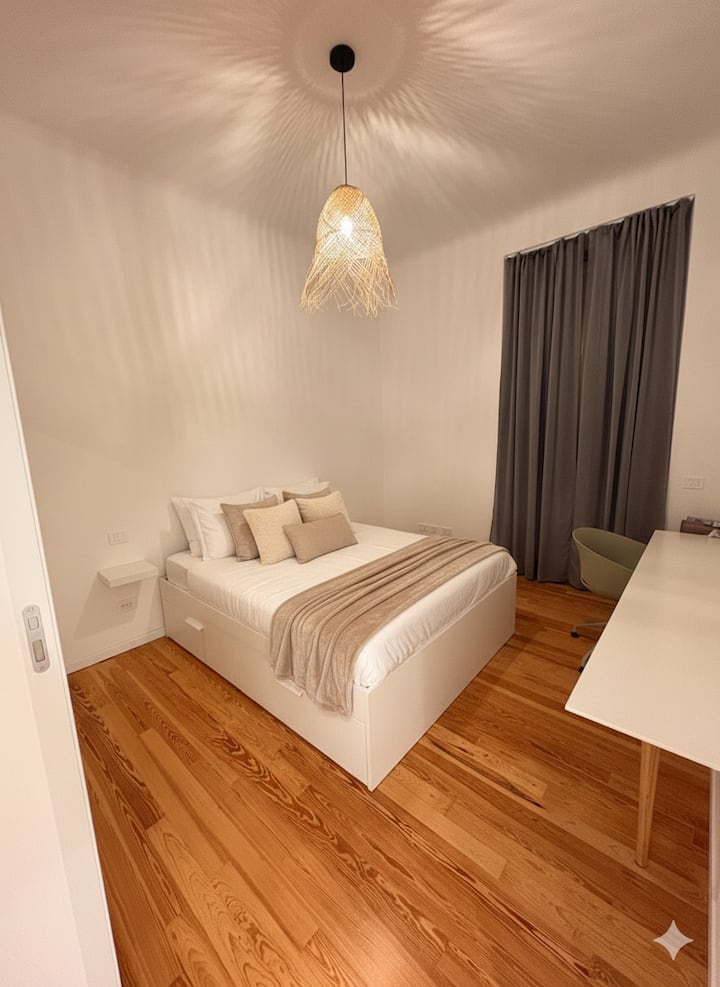 Relájate en este dormitorio sereno con suelos de parquet de madera fina y una cómoda cama doble con almacenamiento incorporado. El espacio incluye un escritorio dedicado con silla de oficina para trabajo remoto y un baño privado para tu comodidad.