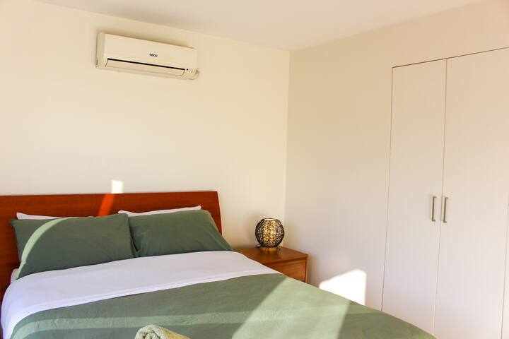 Dormitorio orientado al oeste en el último piso con cama tamaño queen y baño privado. Mucha luz natural y un balcón con puertas plegables.