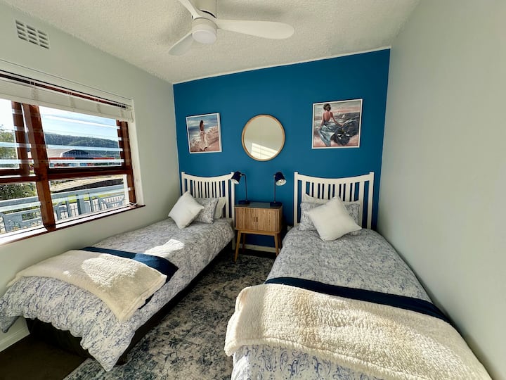 Aurinkoinen makuuhuone, jossa on kaksi yhden hengen vuodetta ja ylelliset vuodevaatteet