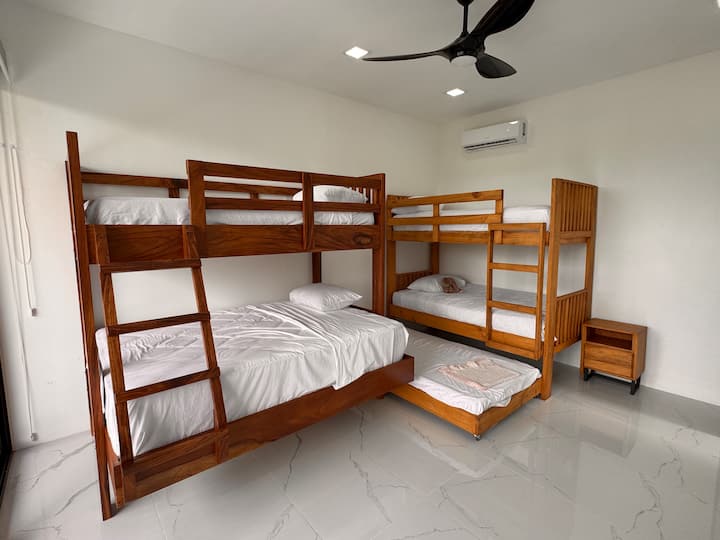 Esta espaciosa habitación con literas es perfecta para familias o grupos, con dos robustas literas de madera y una cómoda cama nido. Con aire acondicionado fresco, elegantes suelos de baldosas y un amplio espacio, es un refugio cómodo y divertido para niños o invitados adicionales.