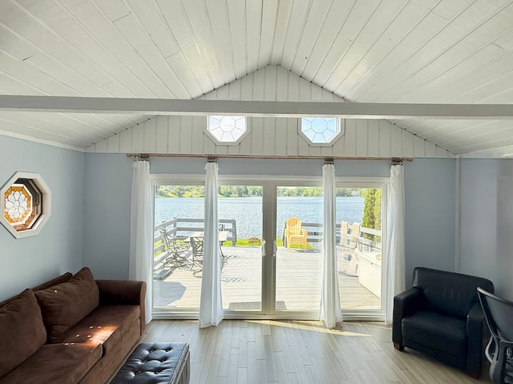 Sala de estar luminosa y acogedora con sofá cama extraíble completo, TV inteligente, escritorio dedicado y configuración de monitor, además de impresionantes vistas al lago y acceso directo a la terraza.