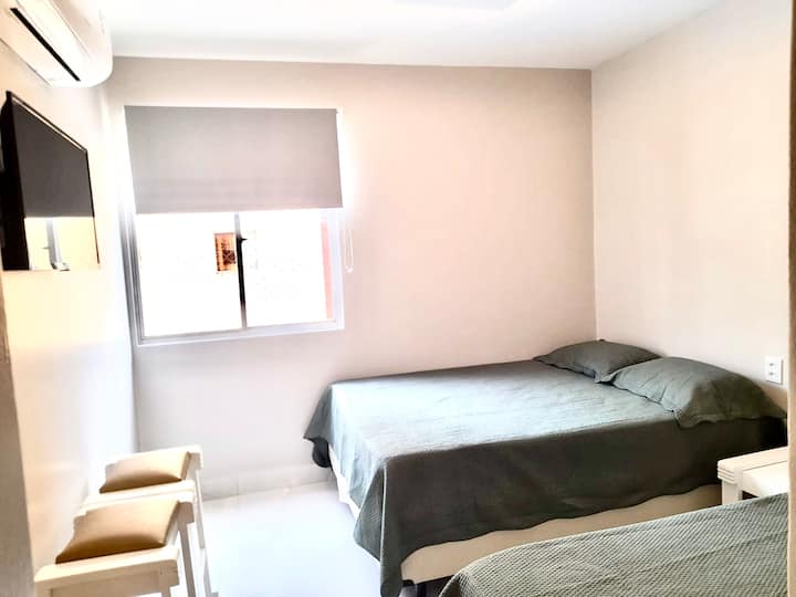 Изглед към апартамент 2, с 1 двойно легло, 1 единично легло, климатик, телевизор, прозорец с изглед към частния воден парк на жилищния блок и самостоятелна баня. 