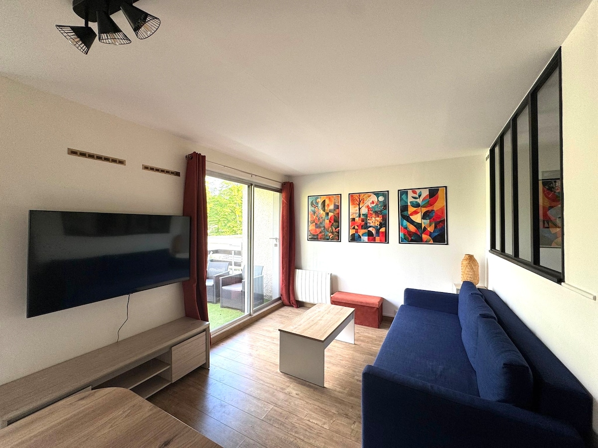 A bright living area is featured, furnished with a navy blue sofa and a contemporary coffee table. Large sliding doors open to a private outdoor space, while colorful artwork adorns the walls. Natural light is invited into the space, creating a vibrant atmosphere.