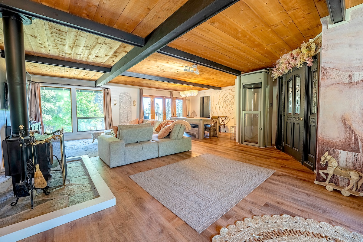 Living room with wood burning fireplace, huge TV, big dining table that can be converted into a pool or ping pong table. Upper deck entrance to BBQ area. Elevator to the lower floor