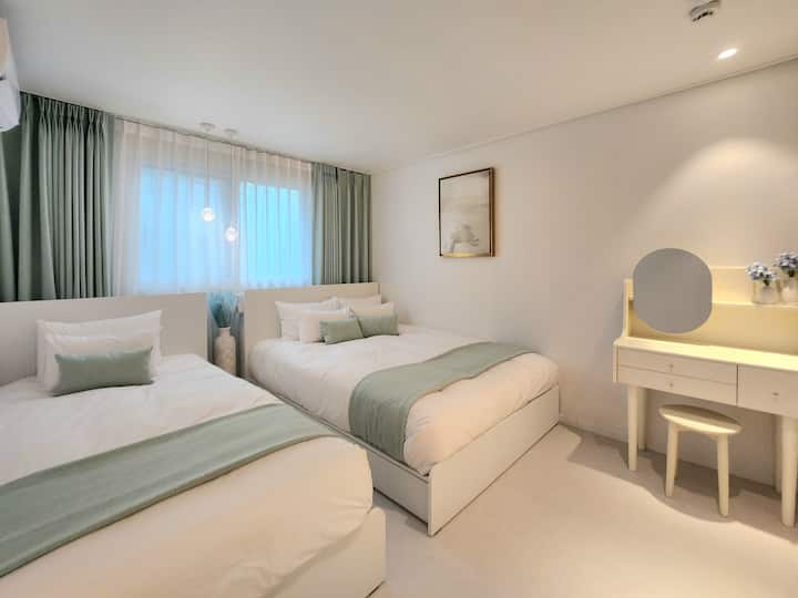 Ова е спална соба 1 во Salu Stay каде што можете да се чувствувате светло во теписи, перничиња и завеси во боја на нане. Има посебен тоалет и маса за облекување за вашето приватно време. Особено се препорачува за семејства со мали деца бидејќи има голем брачен кревет и кревет за едно лице со луксузна постелнина во хотелски стил со лесни, но топли јоргани од гуски. Уметничките дела и дизајнерските вазни на Никола де Стал создаваат релаксирачки момент што ви го топли срцето.
