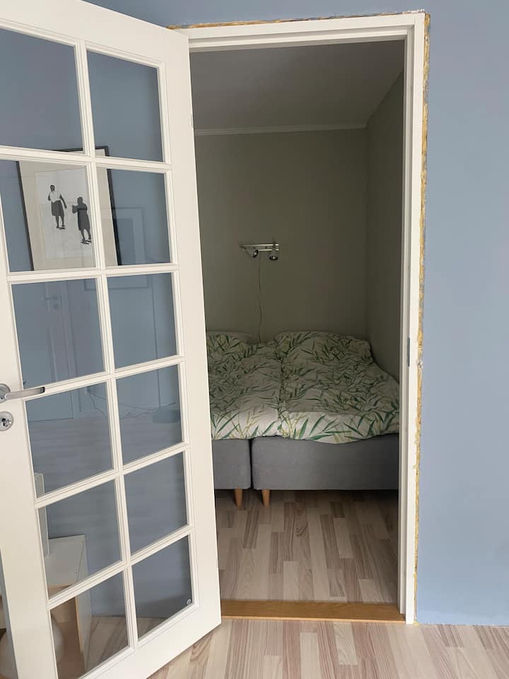 غرفة نوم بسرير مزدوج، صندوق زنبركي من ميو. باب زجاجي مع ستائر باتجاه غرفة المعيشة. مبني حديثًا - ستكون الشرائط 