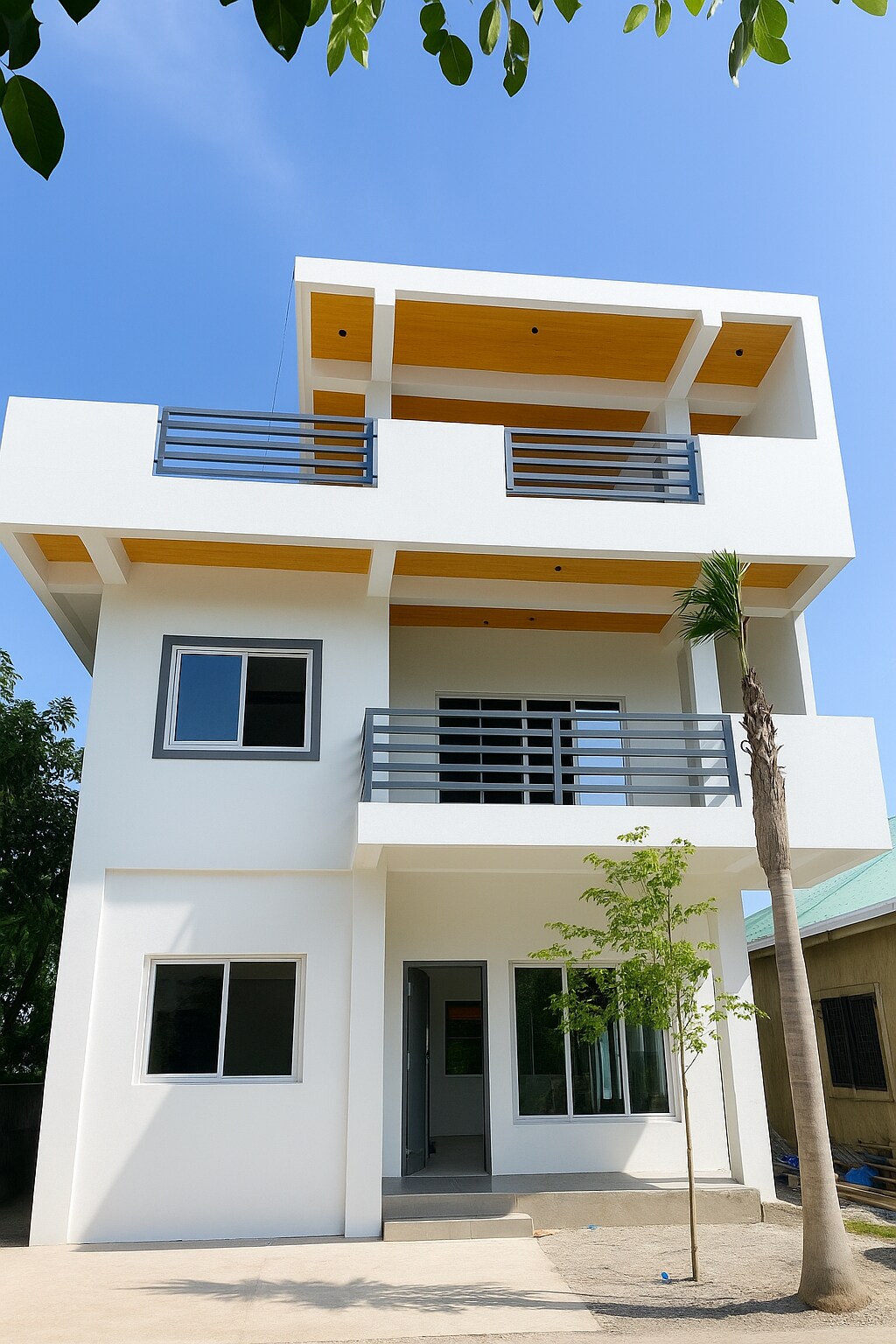 A modern three-story house is depicted, featuring a clean white exterior complemented by wooden accents on the top floor. The facade includes several large windows, and a balcony is visible on the second level. A small tree is positioned in front of the main entrance.