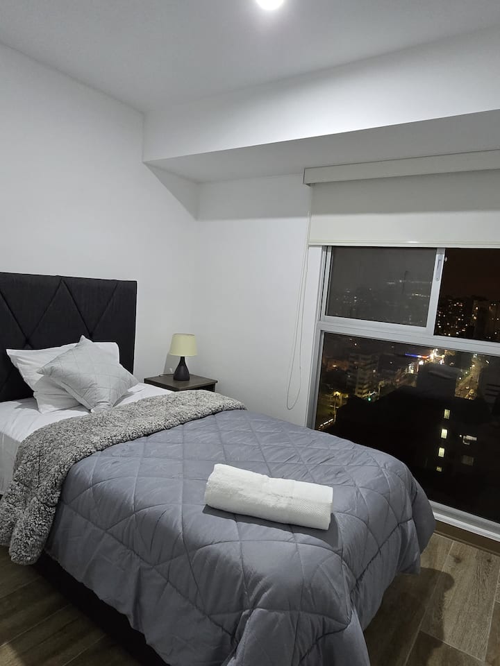 Habitación con cama de 1.5 plazas. Cuenta con closet, lámpara y hermosa vista a la calle.