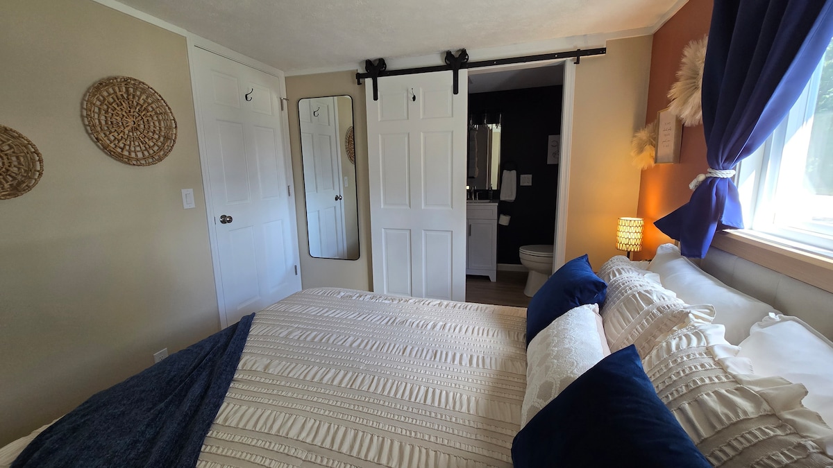 Boho-geïnspireerde hoofdslaapkamer met queensize bed, aangrenzende complete badkamer, verduisteringsgordijnen en gezellig comfort. 