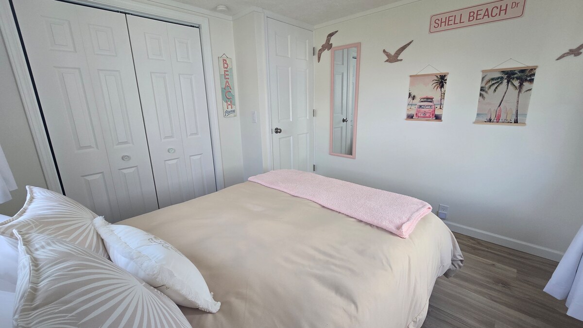 Onze slaapkamer met strandthema beschikt over een gezellig full-size bed met een zachtroze accentdeken, verduisteringsgordijnen voor een goede nachtrust en een volledige lengte spiegel met dressoirruimte in de kast. Een kleine vloerventilator is te vinden in elke kast slaapkamer, indien nodig.