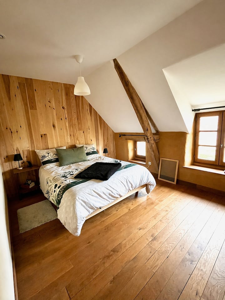 Master bedroom under the roof beams - solid wood flooring, natural light, farmhouse atmosphere