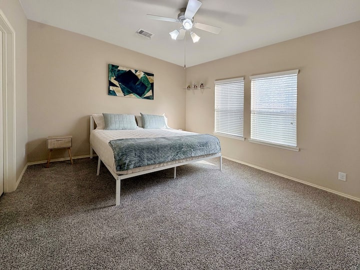Bedroom Bliss: Relax in a sunlit retreat with vibrant art and plush carpet. Perfect for unwinding!