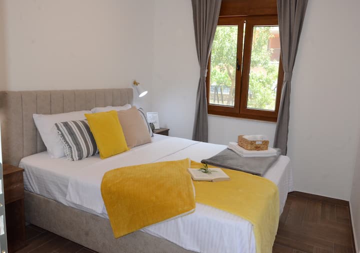 Ova soba odiše toplinom i udobnošću, uz naglasak na jednostavnom, ali pažljivo uređenom interijeru.
Krevet zauzima središnje mjesto i izgleda vrlo pozivajuće, s tapeciranim uzglavljem u nježnoj bež boji.
